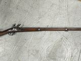 Un vieux fusil est posé par terre dans une pièce.