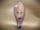 a wooden mask with a blue tie on a leather surface