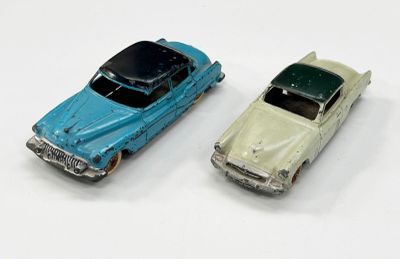 deux voitures jouets assises l'une à côté de l'autre sur une surface blanche