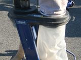 un sac posé sur un chariot, auquel est raccordé un tuyau