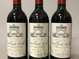 trois bouteilles de vin rouge posées sur une table blanche