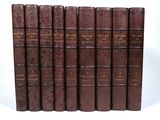six old books are lined up in a row on a white surface