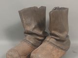 une paire de bottes en cuir marron posées sur une surface blanche