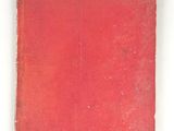 un vieux livre rouge posé sur une table blanche