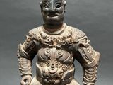 an old statue of a man sitting on top of a wooden block