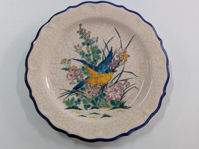 a plate with a bird painted on it sitting on a table