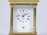 une petite horloge en or avec des chiffres romains