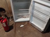 an open refrigerator sitting next to a fire extinguisher