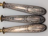 three antique silverware spoons are sitting on a white surface
