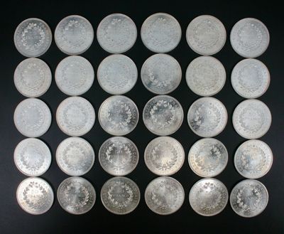 Plusieurs pièces d'argent sont disposées en carré sur une surface noire