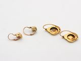 three pairs of gold earrings and a ring on a white surface