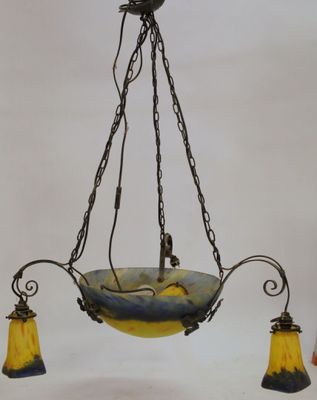 an old fashioned chandelier hanging from a ceiling with three yellow glass lamps
