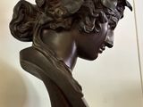 a bronze bust of a woman with a flower in her hair