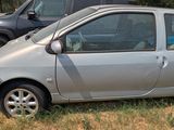 a small silver car parked in the grass next to a black truck