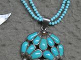 collier composé de perles de turquoise et d'un pendentif en argent orné d'un oiseau