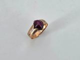 a close up of a gold ring with a purple stone