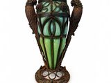 un vase vert surmonté de deux oiseaux