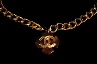 a close up of a gold chain with a brown pendant