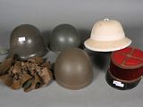 three helmets, a hat, and a spool of thread sit on a table