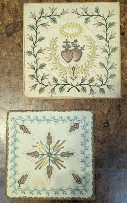 two pieces of embroidery on a table with a heart and a cross