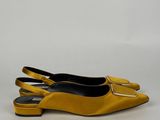 une paire de chaussures jaunes posées sur une surface blanche, avec un fond blanc
