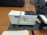 a white machine sitting on top of a table next to a movie projector