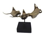brass sculpture of two fish on a black stand on a white background