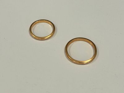 deux alliances en or posées sur une table blanche