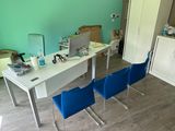 a white desk with blue chairs and a computer on it