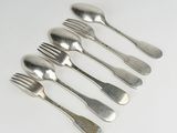 six fourchettes et cuillères sont disposées en ligne sur une surface blanche