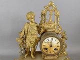 a gold clock with a statue of a boy on top of it
