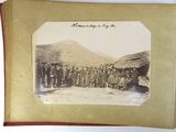 an old photo of a group of people standing in front of a hut
