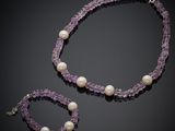 a close up of a necklace and bracelet with pearls on a black background