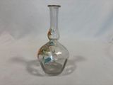a glass vase with a bird on it sitting on a table