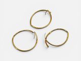 trois paires de boucles d'oreilles créoles en or sur fond blanc