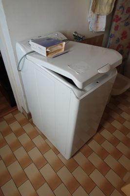 une petite machine à laver blanche dans un coin de la pièce