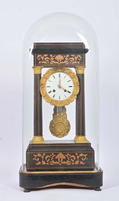 une petite horloge sous un dôme de verre sur une table