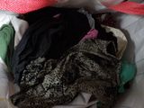 a pile of clothes on a bed with a hat on top of it