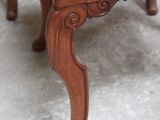 a small wooden chair with a red cushion on top of it