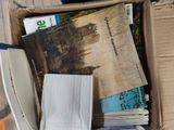a cardboard box full of books and magazines on the floor
