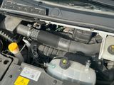 un moteur de voiture dont le capot est ouvert et sur lequel est posé un bouchon jaune