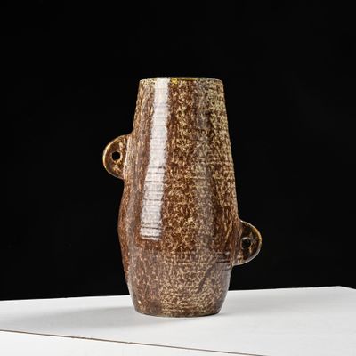 un vase marron posé sur une table blanche