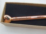 a rose gold pen in a box on a table