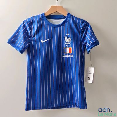 Le t-shirt est bleu et blanc, avec une rayure blanche.