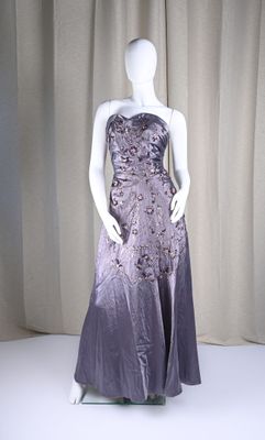 mannequin dressed in a purple dress on display in front of a curtain
