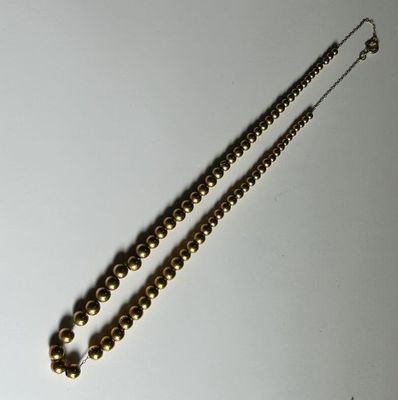 necklace with gold beads on a white surface with a silver chain