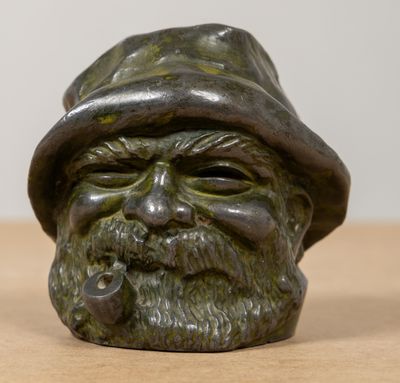 une statue représentant un homme coiffé d'un chapeau et tenant une pipe à la bouche