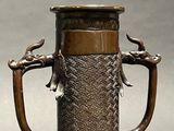 a bronze vase with a handle and a bird on it