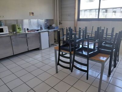 tables and chairs in a kitchen with a refrigerator in the background
