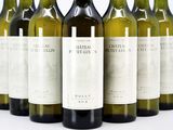 six bottles of white wine lined up in a row on a white surface